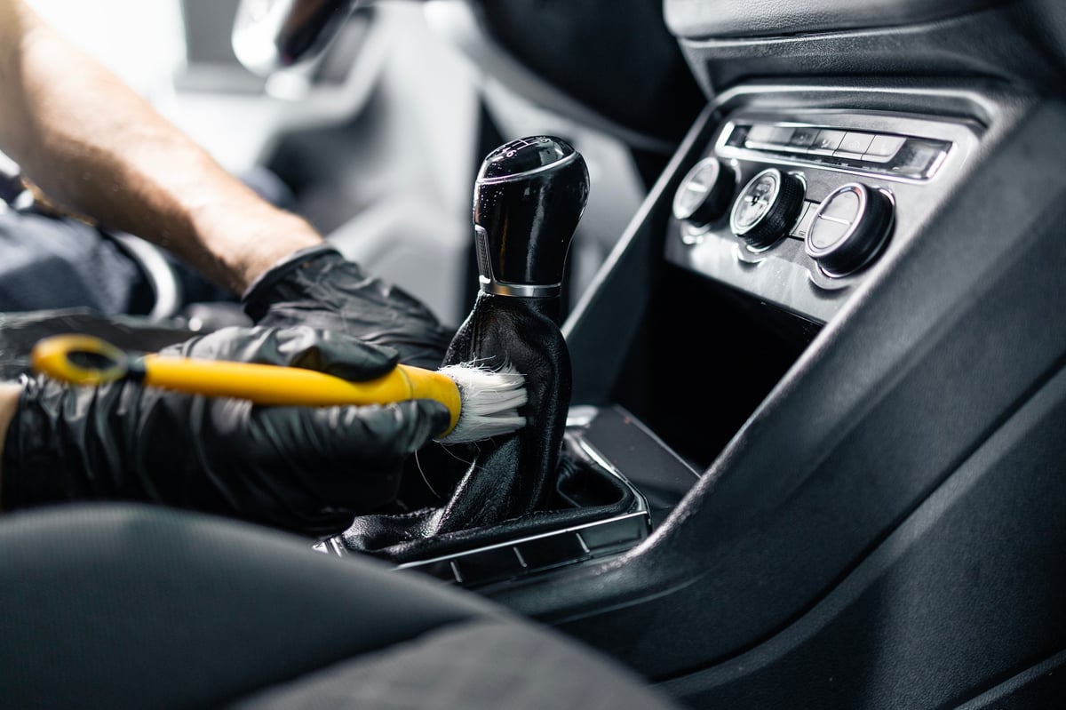 Detailer cleaning the inside of a car interior with a soft brush